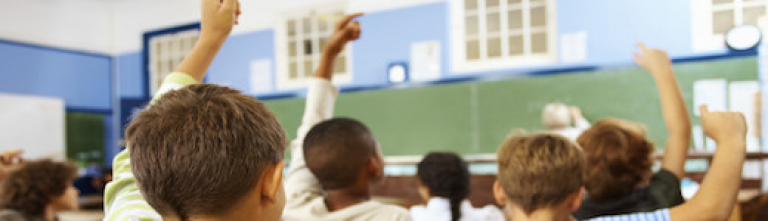 Rear view of a little school boy at his classroom kids-raised-hands-class-520x150